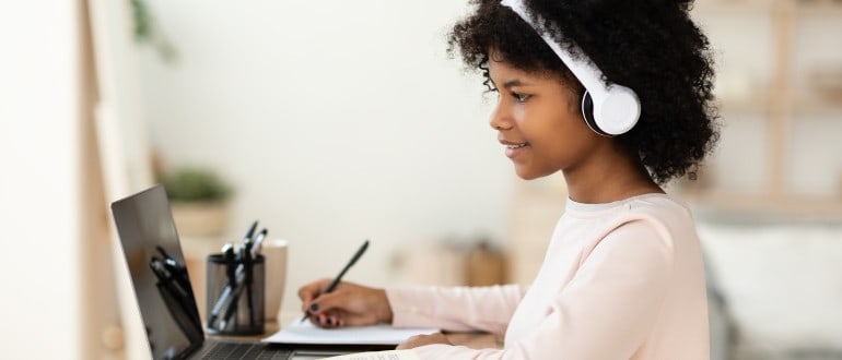 female student studying on laptop while wearing headphones