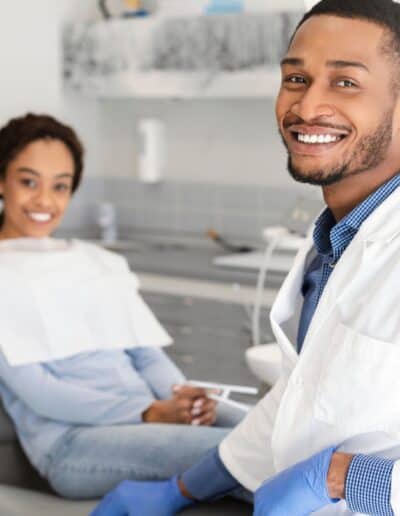 Black dentist doctor and patient in chair smiling at camera stock photo